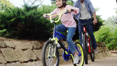 Father-and-daughter-cycling-in-park