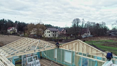 People-working-on-frame-of-wooden-House-construction-in-Riga,-Latvia