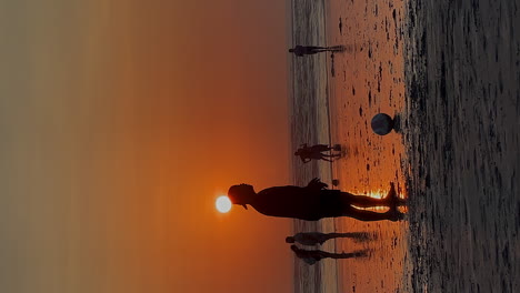 Formato-Vertical:-Silueta-De-Hombres-Jugando-Al-Fútbol-En-La-Playa-Dorada-Al-Atardecer