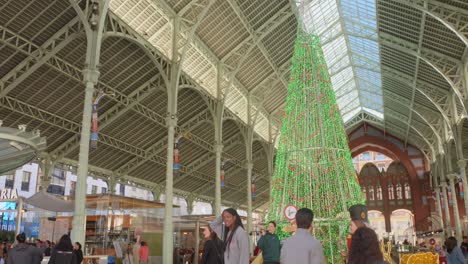 Toma-Inclinada-Hacia-Abajo-De-Caminar-Por-Una-Calle-Con-El-árbol-De-Navidad-Gigante-En-El-Centro-De-Valencia,-España-Durante-El-Día.