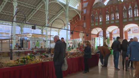 Shot-of-locals-walking-around-a-street-market-stall-in-the-Mercado-de-Colon-in-Valencia,-Spain