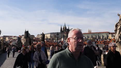 People-crossing-the-Charles-Bridge-in-Prague,-Czech-Republic