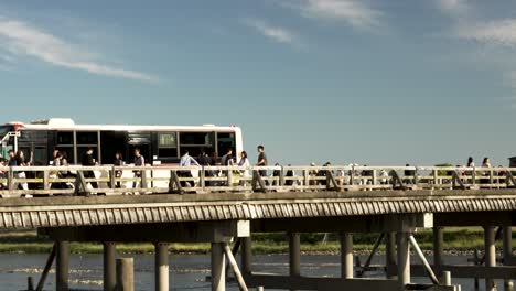 Gente-Asiática-Cruzando-El-Concurrido-Puente-Togetsukyo-En-Arashiyama,-Kyoto,-Japón,-Durante-El-Día