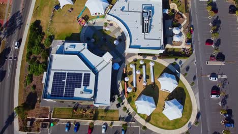 Vista-Panorámica-De-Edificios-Con-Energía-Solar-En-La-Azotea,-Carpas-De-Cúpula-Blanca-En-El-Césped-Listas-Para-El-Evento