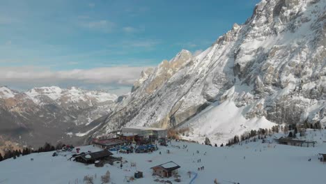 Drone-shot-of-Ciampac-ski-resort,-focusing-on-the-bustling-arrival-area-of-the-main-cable-car