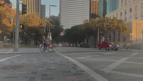 Una-Foto-En-Primera-Persona-De-Una-Bicicleta-Cruzando-Una-Calle-Y-Un-Ciclista-Esperando-En-Un-Semáforo-En-Bagby-En-El-Centro-De-Houston,-Texas.