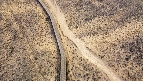 Toma-Aérea-Inclinada-Hacia-Arriba-Del-Camino-De-Las-Dunas-De-Arena-Y-El-Océano-Atlántico-Azul-Durante-La-Puesta-De-Sol-Dorada-En-Portugal