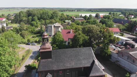 Black-wooden-church-with-dark-bell-tower-and-golden-ball-spire-in-rural-village