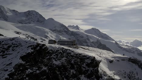 Drone-flies-over-Rifugio-Quintino-Sella-al-Felik,-heading-towards-the-iconic-Lyskamm-peaks-and-glaciers-in-the-Monte-Rosa-group