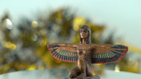 Dreamy-close-up-shot-of-a-Cleopatra-statue-with-wide-open-wings,-shiny-golden-depth-of-field,-ancient,-Egyptian-historical-ruler,-antique-artwork-of-a-goddess,-rotating-360-cinematic-4K-video-tilt-up