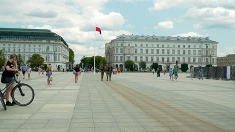 Ambiente-Animado-En-La-Plaza-Pilsudskiego-De-La-Ciudad-De-Varsovia,-Con-Un-Telón-De-Fondo-De-Edificios-Majestuosos-Y-La-Bandera-Nacional.