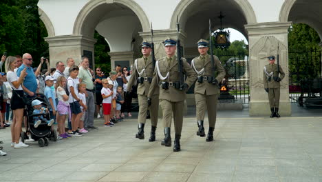 Uniformed-guards-in-a-ceremonial-Tomb-of-the-Unknown-Soldier,-march-past-the-eternal-flame-at-a-Warsaw-memorial---Piłsudski-Square