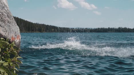 Two-young-adults-cliff-jumping-into-lake,-slow-motion