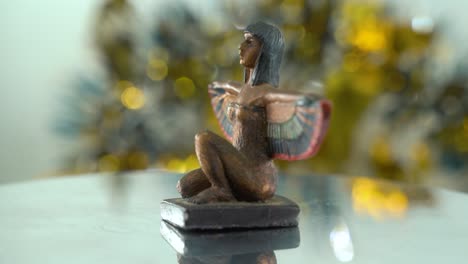 Primer-Plano-De-Ensueño-De-Una-Estatua-De-Cleopatra-Con-Las-Alas-Abiertas,-Profundidad-De-Campo-Dorada-Brillante,-Antiguo-Gobernante-Histórico-Egipcio,-Obras-De-Arte-Antiguas-De-Una-Diosa,-Vídeo-Giratorio-360-Suave-E-Inclinado-Hacia-Abajo