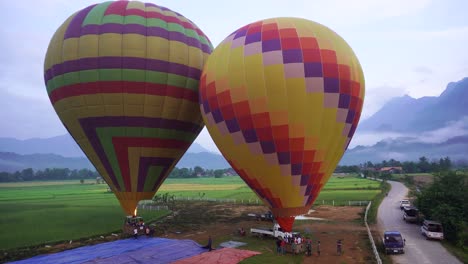 Zwei-Heißluftballons-Werden-Für-Den-Start-Auf-Einem-Ländlichen-Feld-In-Vang-Vieng,-Laos,-Vorbereitet