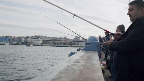 Türkische-Fischer-Auf-Der-Galata-Brücke-Beim-Angeln-Mit-Blick-Auf-Die-Stadt-Istanbul-Im-Hintergrund