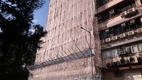 An-unfinished-addition-to-a-simple-apartment-unit-with-a-backdrop-of-windblown-trees-in-downtown-Victoria-in-Hong-Kong,-China