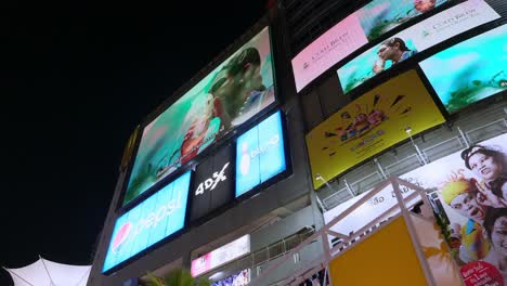 Vallas-Publicitarias-Digitales-Que-Anuncian-Simultáneamente-Diferentes-Productos-Frente-A-Un-Centro-Comercial-Comunitario-En-Un-Centro-De-Negocios-En-Bangkok,-Tailandia