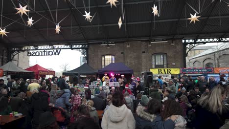 Multitudes-Disfrutando-De-Una-Actuación-Musical-Festiva-De-Una-Banda-En-El-Canopy-Market-Durante-La-Navidad-En-Diciembre-En-Kings-Cross,-Londres