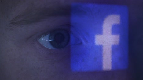 Primerísimo-Plano-Del-Ojo-De-Un-Joven-Mirando-El-Logo-De-Facebook-A-Altas-Horas-De-La-Noche