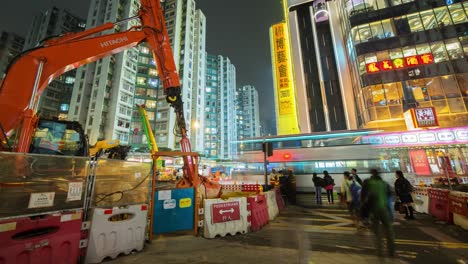 Zeitraffer-Einer-Belebten-Straße-Und-Eines-Einkaufszentrums-In-Hongkong-Neben-Der-Baustelle,-Auf-Der-Eine-Neue-U-Bahn-Station-Gebaut-Wird.-Während-Die-Menschen-Vorbeieilen,-Sorgen-Die-Aufzüge-Im-Einkaufszentrum-Für-Textur