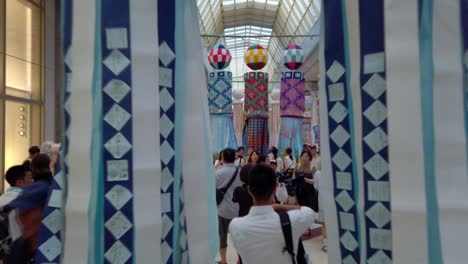 People-in-arcade-walking-through-decorative-paper-streamers-during-Tanabata-festival