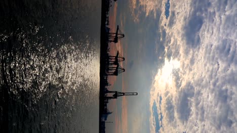 Grúa-De-Contenedores-En-La-Isla-Bukom-En-El-Fondo-Del-Atardecer-Detrás,-Tomada-Desde-El-Embarcadero-De-Labrador