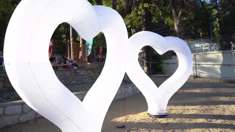 Corazones-Inflables-Exhibidos-En-La-Playa-Con-Gente-Caminando-Al-Fondo.