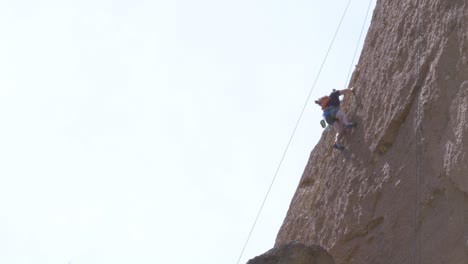 Escalador-Escalando-Una-Estructura-De-Roca-Roja