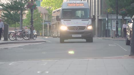 Cars-driving-down-a-street-with-pedestrians-walking-on-either-side