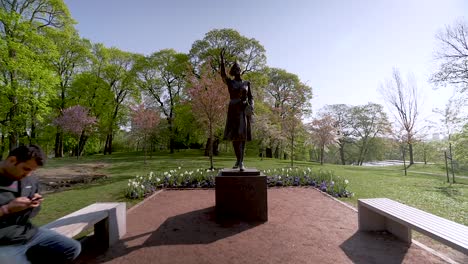 Gimbal-shot-of-a-person-sitting-in-front-of-a-statue-in-the-park-at-the-Royal-Palace-of-Oslo,-Norway