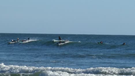 multiple-surfers-in-wetsuits-trying-to-get-up-on-the-same-wave-party-wave-pan-right-to-left