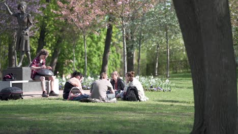 Un-Grupo-De-Personas-Se-Reunieron-Para-Un-Picnic-Mientras-Una-Persona-Toca-Un-Tambor-En-El-Parque-Del-Palacio-Real-De-Oslo,-Noruega