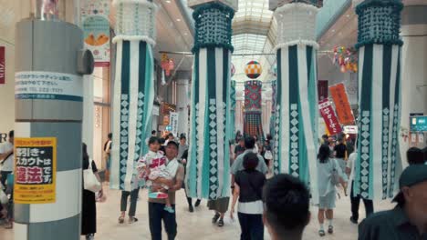 People-on-busy-street-walking-through-decorative-paper-streamers-during-Tanabata-festival-in-slow-motion