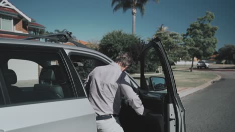 Man-walking-towards-a-parked-car-and-getting-into-the-car