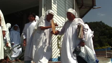 A-very-old-woman-wearing-white-dress-is-having-difficulty-in-going-down-the-stairs-from-a-church-Another-women-are-helping-her