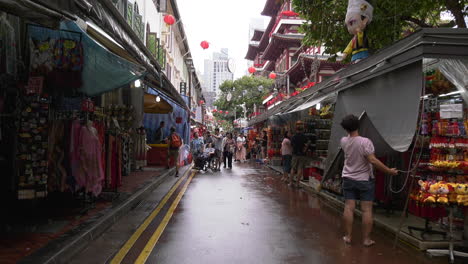 A-street-in-Chinatown-beside-a-temple-with-people-walking-about,-Singapore