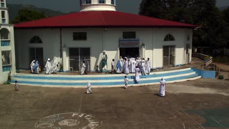 people-with-white-clothing-are-outside-a-church-chapel-on-a-sunny-and-hot-day