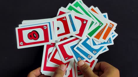 Male-hands-lay-out-colorful-Uno-playing-cards-on-a-black-table