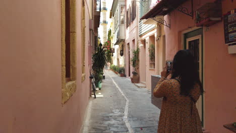 Black-haired-girl-making-a-picture-of-a-tower-in-a-cozy-street-in-Crete,-Greece