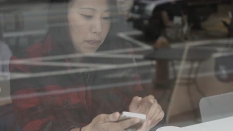 Young-Millenial-in-Plaid-Checks-he-iPhone-while-finishing-her-coffee