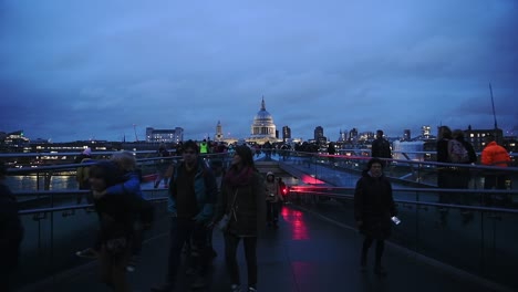 Gente-Caminando-En-El-Puente-Del-Milenio-En-Londres,-Reino-Unido,-Con-La-Antigua-Catedral-De-San-Pablo-Al-Fondo-Por-La-Noche---Plano-Amplio