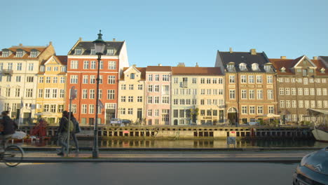 Famoso-Monumento-Danés-De-Las-Coloridas-Casas-De-Nyhavn-En-Copehague,-La-Gente-Y-La-Bicicleta-Pasan