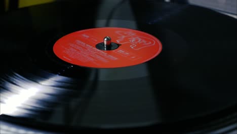 A-black-vintage-vinyl-record-with-red-centre-disk-spins-on-a-turntable