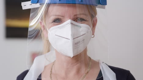 A-shot-of-a-female-physiotherapist-laughing-into-the-camera-while-wearing-a-protection-mask-during-the-corona-crisis