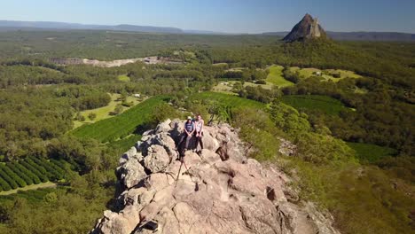 Drone-Aéreo-Disparado-Desde-Una-Pareja,-Un-Hombre-Y-Una-Mujer-Caminando-En-Una-Montaña-Rocosa,-En-Un-Día-Soleado,-En-El-Parque-Nacional-De-Las-Montañas-Glass-House,-En-Queensland,-Australia