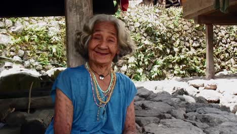 A-native-old-woman-is-talking-under-a-native-grass-hut-shack-in-summertime