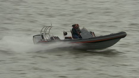 Dos-Personas-En-Un-Bote-Inflable-Rígido-Navegando-A-Través-De-Un-Frío-Mar-Gris-Agitado-Y-Olas