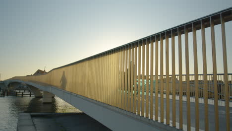 Cyclists-bike-over-bridge-in-Copenhagen,-Denmark-at-sunset