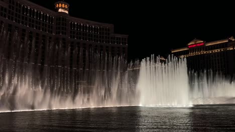 Ciudad-Nocturna,-Vista-A-La-Fuente-Bellagio-En-Las-Vegas-Con-Hoteles-Y-Edificios-De-Lujo-Al-Fondo